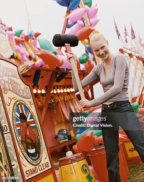 woman holding a large mallet, ready to play an old fashioned strength game, at a fairground - strength tester stock pictures, royalty-free photos & images