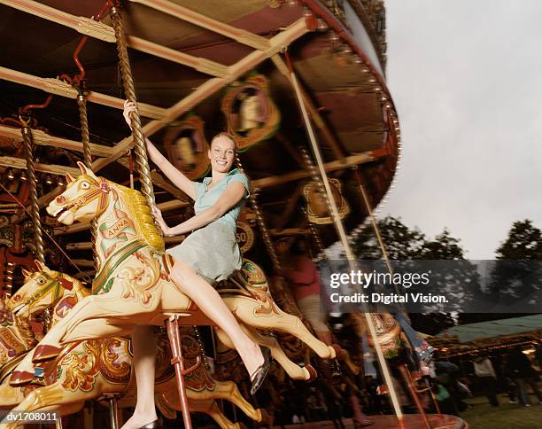 young woman having fun on a fairground carousel - carousel horses stock-fotos und bilder