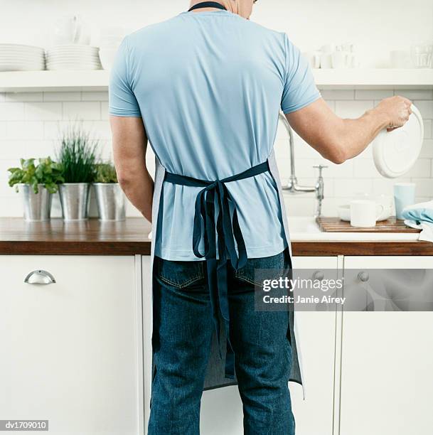 rear view of a man doing the washing up - apron stock pictures, royalty-free photos & images