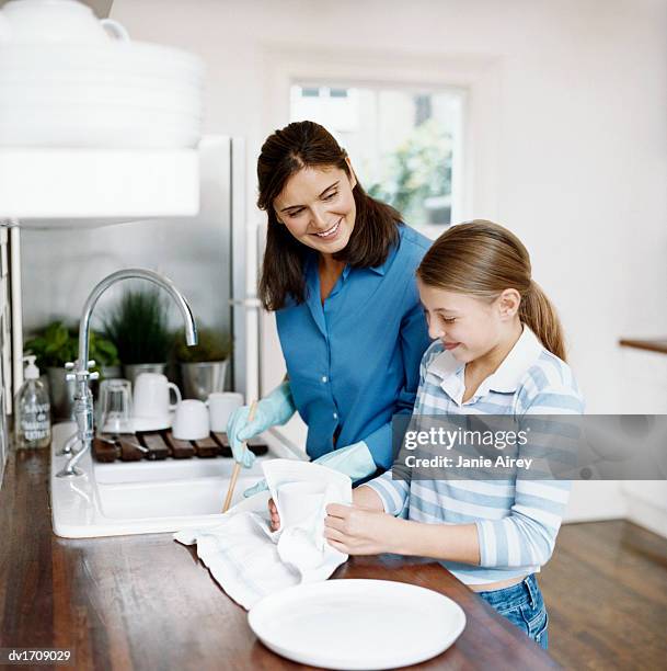 https://media.gettyimages.com/id/dv1709029/photo/young-girl-stands-with-her-mother-at-the-kitchen-sink-helping-her-to-wash-up-and-dry-the-pots.jpg?s=612x612&w=gi&k=20&c=4DcxDioBpGHCy1cEija7vWJhSWCPetEcNjeoRrVaLUI=
