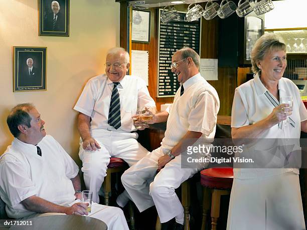 senior men and women dressed in lawn bowling sportswear enjoying a drink in a clubhouse bar - lawn bowling stock-fotos und bilder