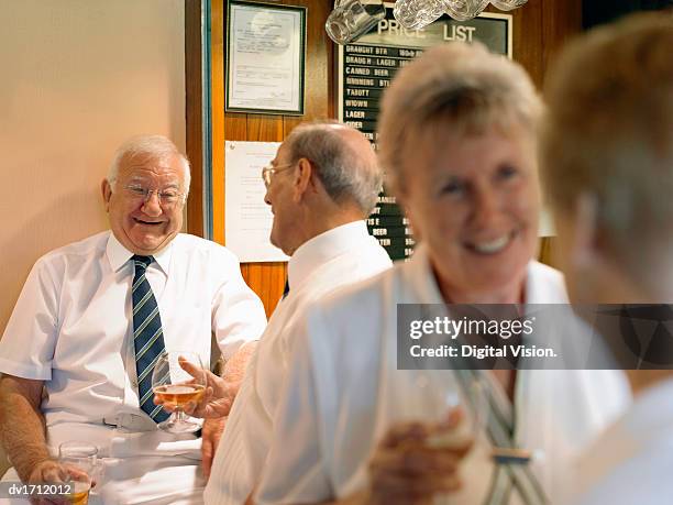 men and women wearing lawn bowling sportswear talking and drinking in a clubhouse bar - lawn bowling stock-fotos und bilder