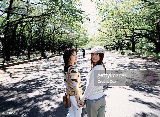 two women holding hands in ueno park, tokyo, japan - taito ward stock pictures, royalty-free photos & images