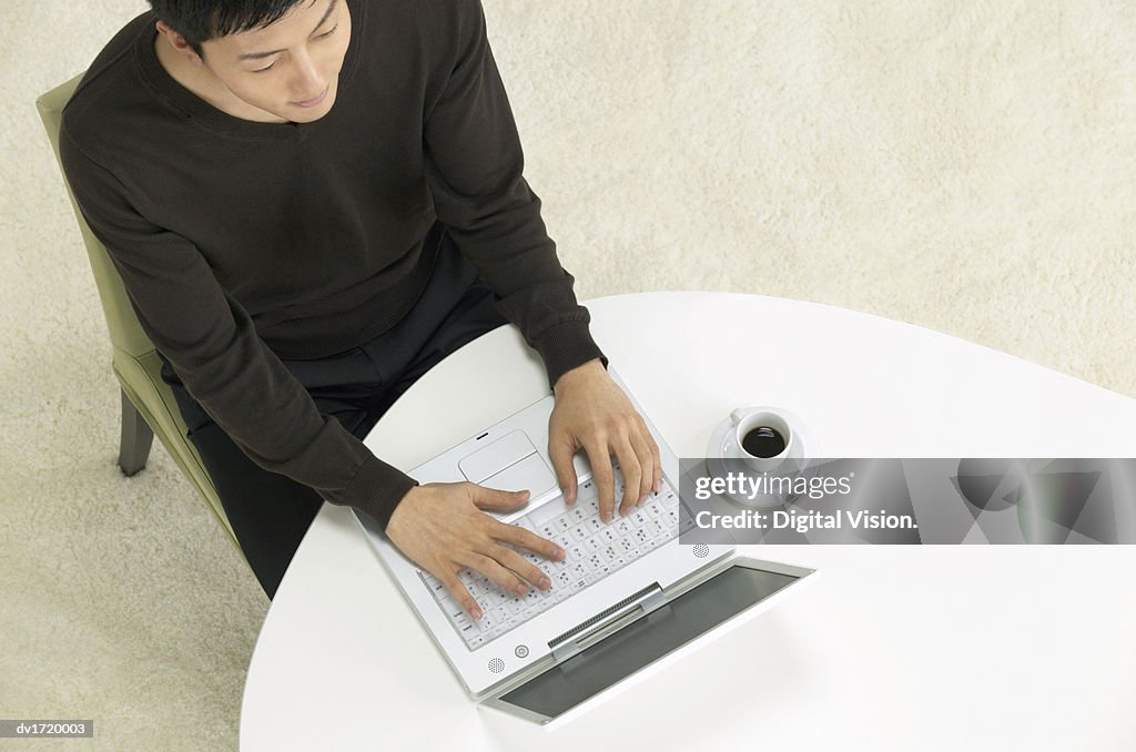 View Directly Above of a Man Sitting at a Table, Using a Laptop