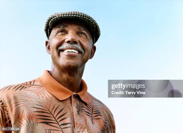 portrait of a senior man wearing a cap and floral print shirt - african american senior man stock pictures, royalty-free photos & images