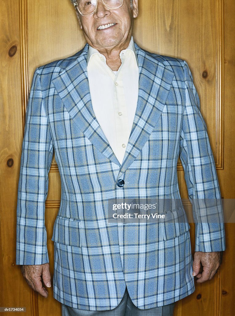 Cropped Portrait of a Senior Man Wearing a Checked Blue Jacket Against a Wooden Background