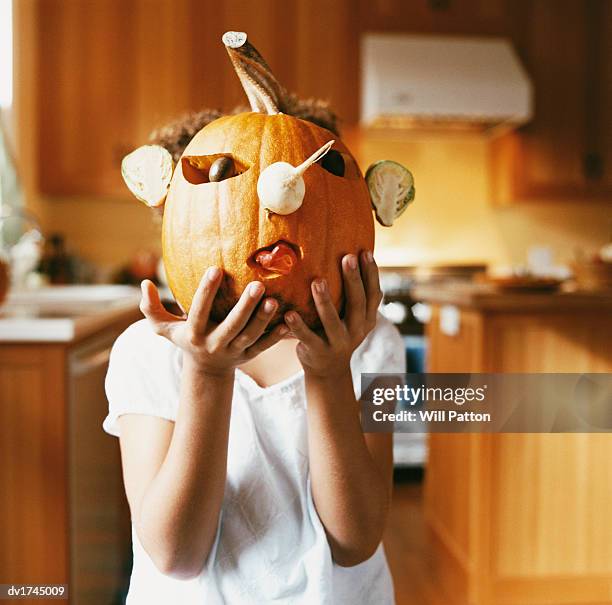 portrait of a girl holding a jack o lantern pumpkin in front of her face - jack o lantern imagens e fotografias de stock