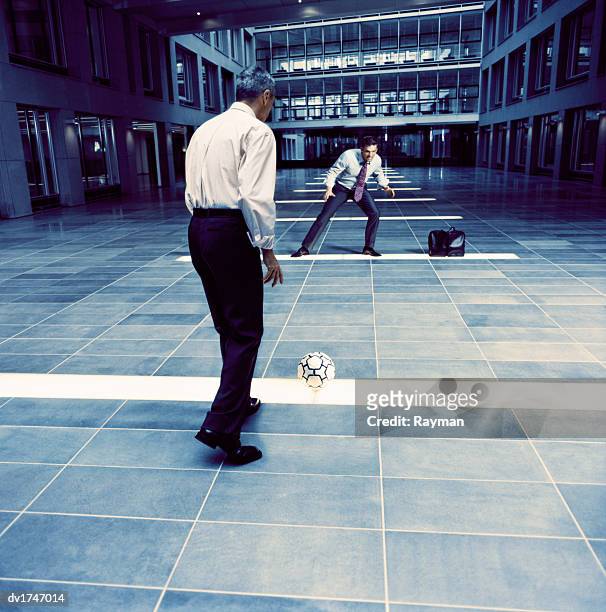 two rival businessmen play football in an office lobby, using briefcases for a goal - kicking bag stock pictures, royalty-free photos & images