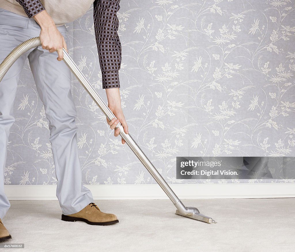 Low Section of a Man Using a Vacuum Cleaner