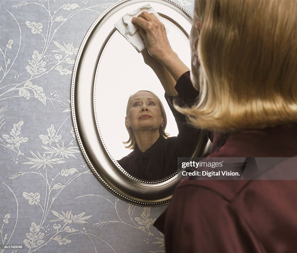 Serious Looking Woman Cleaning a Mirror