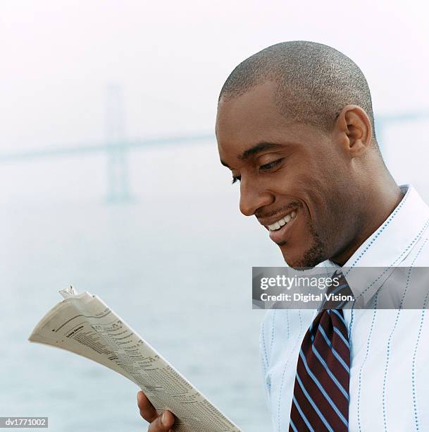 businessman stands reading a paper in mist near the bay bridge - bay bridge fotografías e imágenes de stock