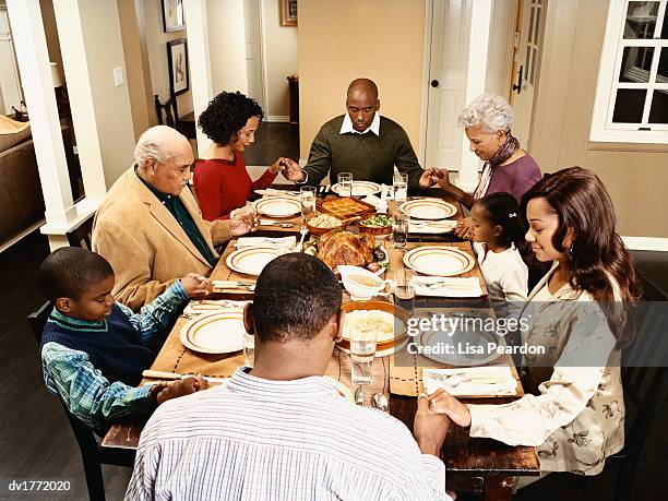 family holding hands and praying before a thanksgiving meal - godsdienstvrijheid stockfoto's en -beelden