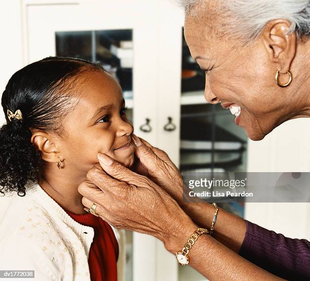 side view of a grandmother squeezing her granddaughter's cheeks - pinching stock pictures, royalty-free photos & images