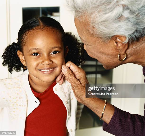 grandmother squeezing her granddaughter's cheek - pincher fotografías e imágenes de stock