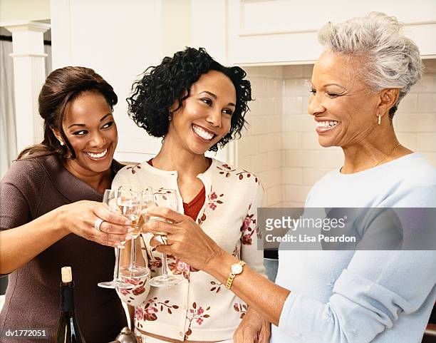 mother stands with her mature daughters raising their glasses in a toast together - adac stock pictures, royalty-free photos & images
