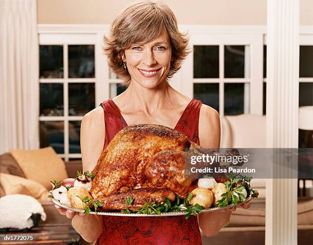 smiling woman carrying a tray with a roast turkey - short hair stock pictures, royalty-free photos & images