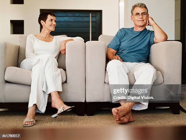 mature couple sit side-by-side in armchairs in their nightwear - vêtement de nuit photos et images de collection