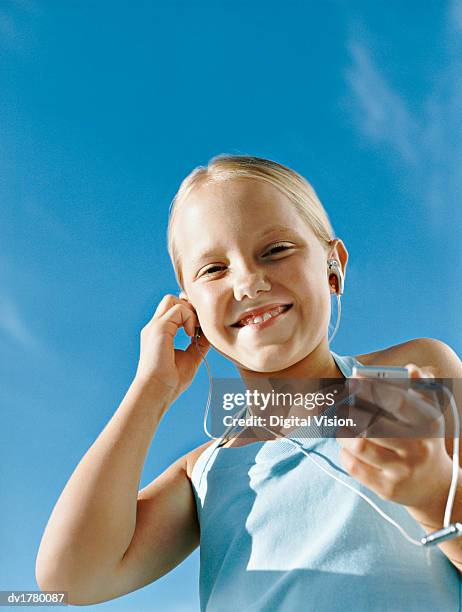 low angle portrait of a young girl listening to an mp3 player with earphones - mp stock pictures, royalty-free photos & images