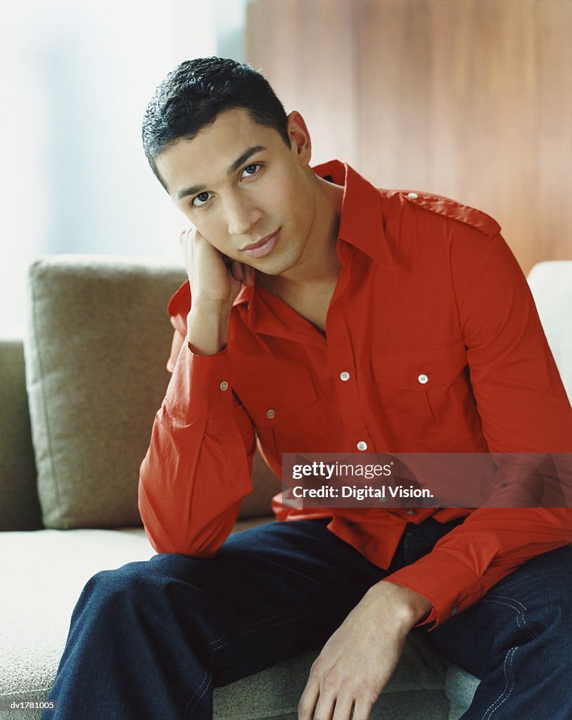 Portrait of a Serious Young Man Sitting on a Sofa