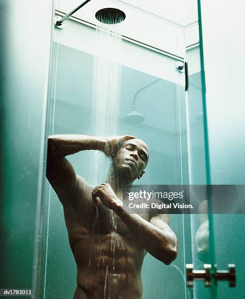 young, muscular man with a shaved head having a shower - shaved head ストックフォトと画像