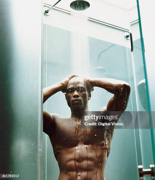 young, muscular man with a shaved head having a shower - shaved head ストックフォトと画像