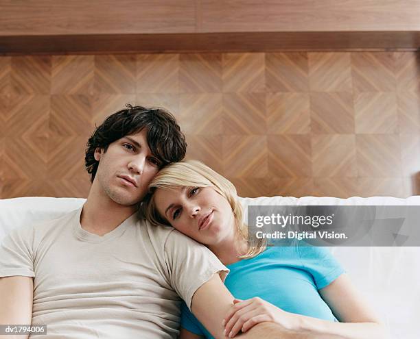 young couple sit together on a bed, wood paneling - morning wood 個照片及圖片檔