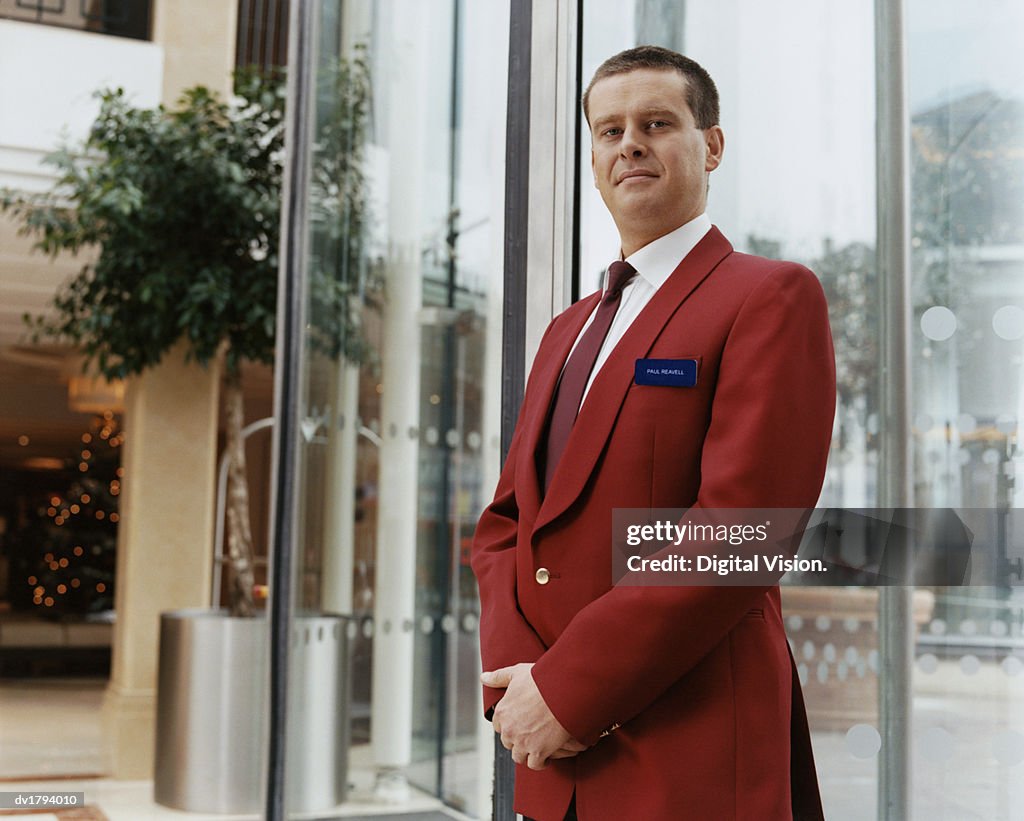 Portrait of a Hotel Doorman in a Smart Red Jacket, Standing in a Lobby by the Entrance