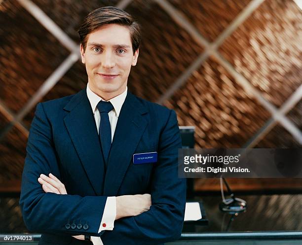 portrait of a male hotel manager standing by a reception desk - name plate stockfoto's en -beelden