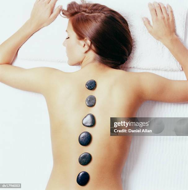 elevated view of a woman lying on a treatment table with six pebbles on her back - massage table white background stock pictures, royalty-free photos & images