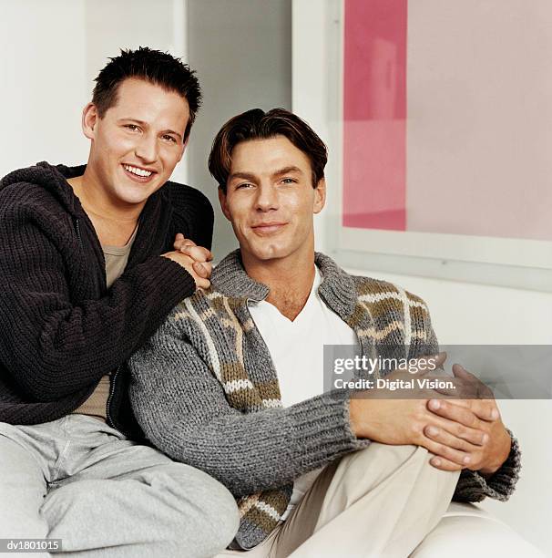 gay couple sitting on sofa - digital devices beside each other bildbanksfoton och bilder