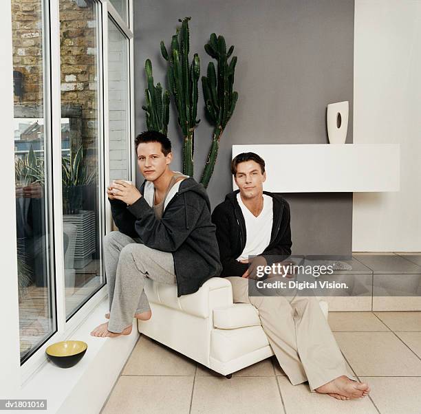 gay couple sitting in armchair - digital devices beside each other bildbanksfoton och bilder