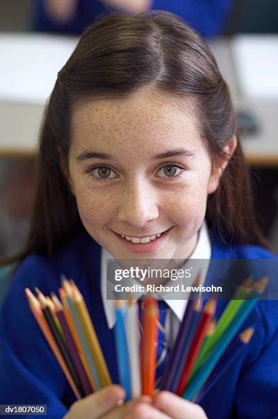 schoolgirl stands holding a variety of multi-coloured pencils - variety stockfoto's en -beelden