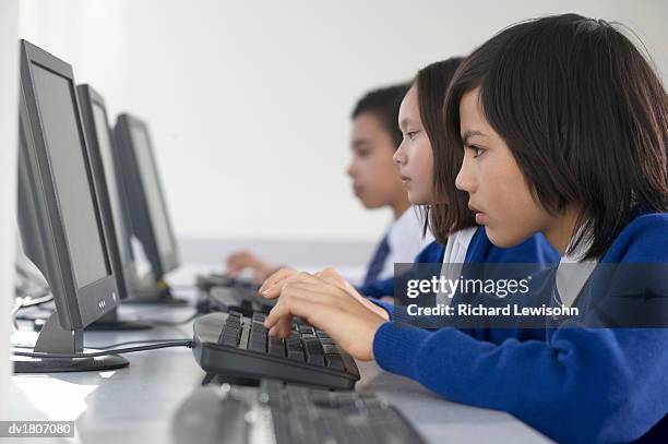 primary schoolboy and girls sitting side by side using pc's - pc 授業 ストックフォトと画像