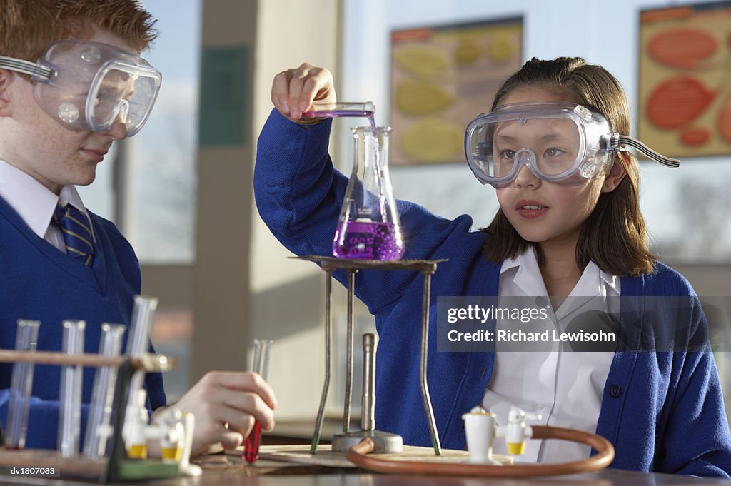 Schoolgirl Pouring Liquid into a Science Flask Watched by a Schoolboy