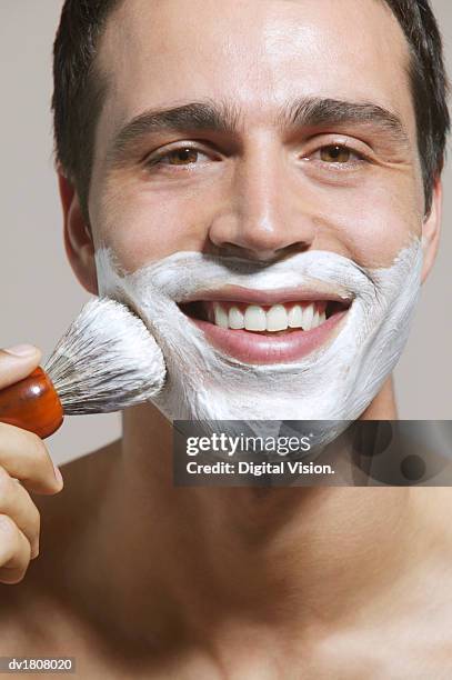 man applies shaving foam to his face with a shaving brush - shaving brush stock pictures, royalty-free photos & images