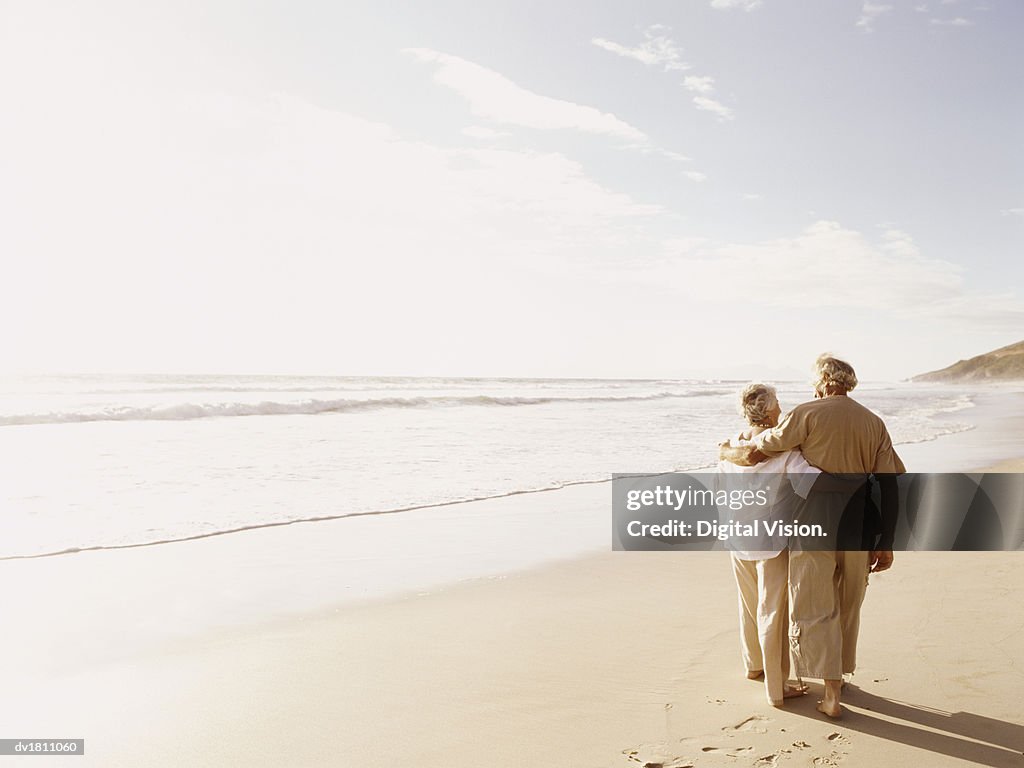Rear View of a Senior Couple Walking on a Beach With Their Arms Around Each Other