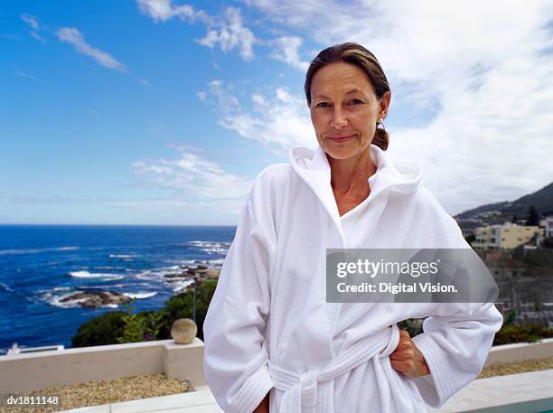 portrait of a senior woman wearing a white dressing gown with the sea in the background - dressing up ストックフォトと画像