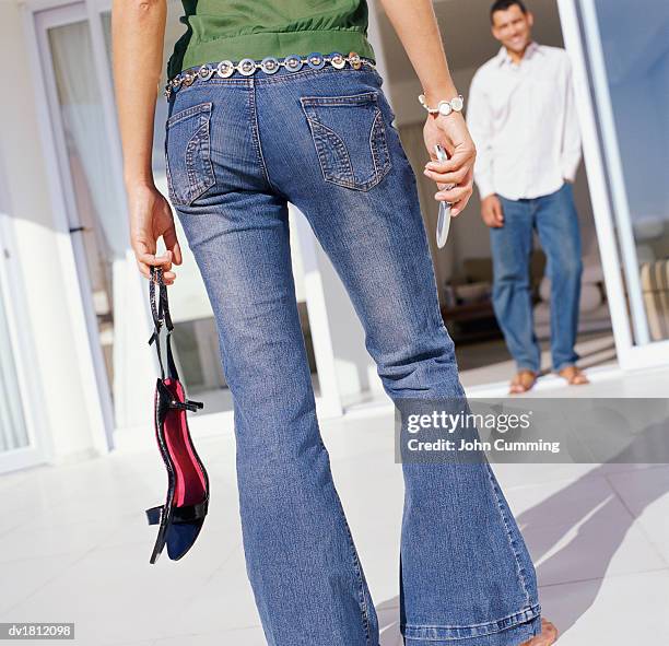 rear view low section shot of a woman wearing flared jeans and holding a mobile phone - flare pants bildbanksfoton och bilder