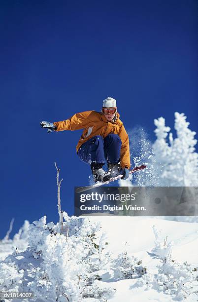 young woman freestyle snowboarding, mid air shot - freestyle snowboarding imagens e fotografias de stock