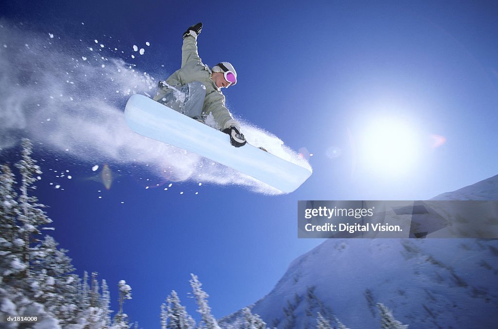 Low Angle Mid Air Shot of a Woman Snowboarding