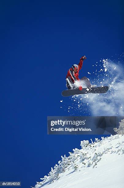 low angle view of a man freestyle snowboarding, mid air - freestyle snowboarding stock pictures, royalty-free photos & images