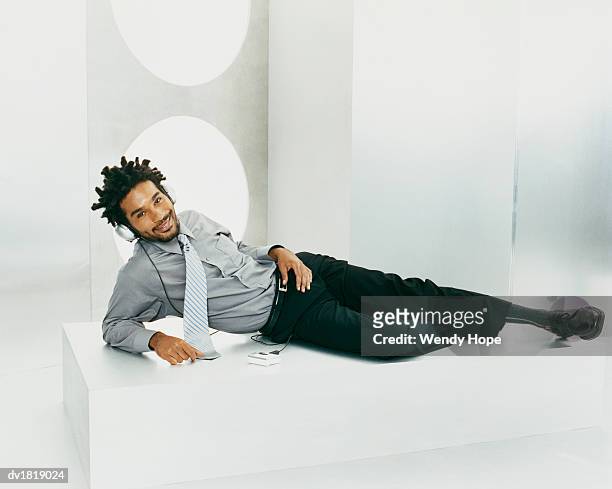 man with dreadlocks listening to music on a personal stereo through headphones - personal stereo stockfoto's en -beelden