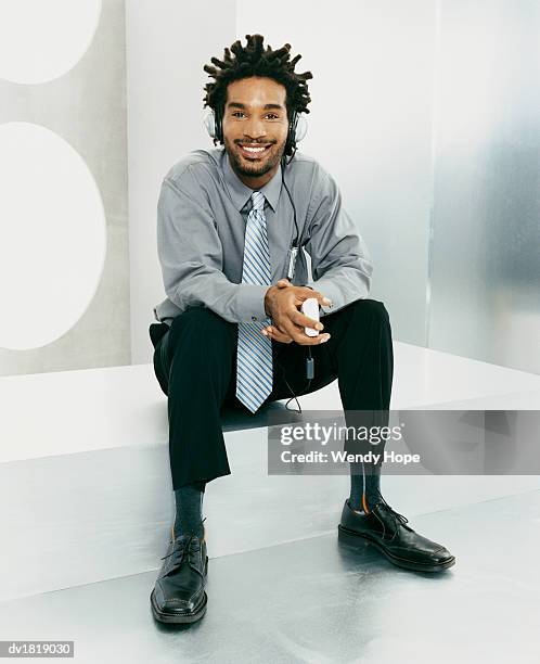 man with dreadlocks sat listening to a personal stereo through headphones - personal stereo stockfoto's en -beelden