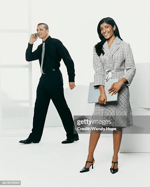 man using a mobile phone and a woman holding a laptop computer - hope imagens e fotografias de stock