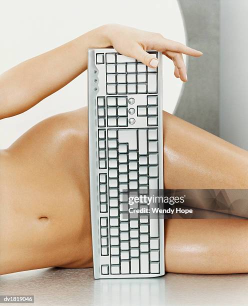 low section shot of a naked woman covering herself with a computer keyboard - hope photos et images de collection