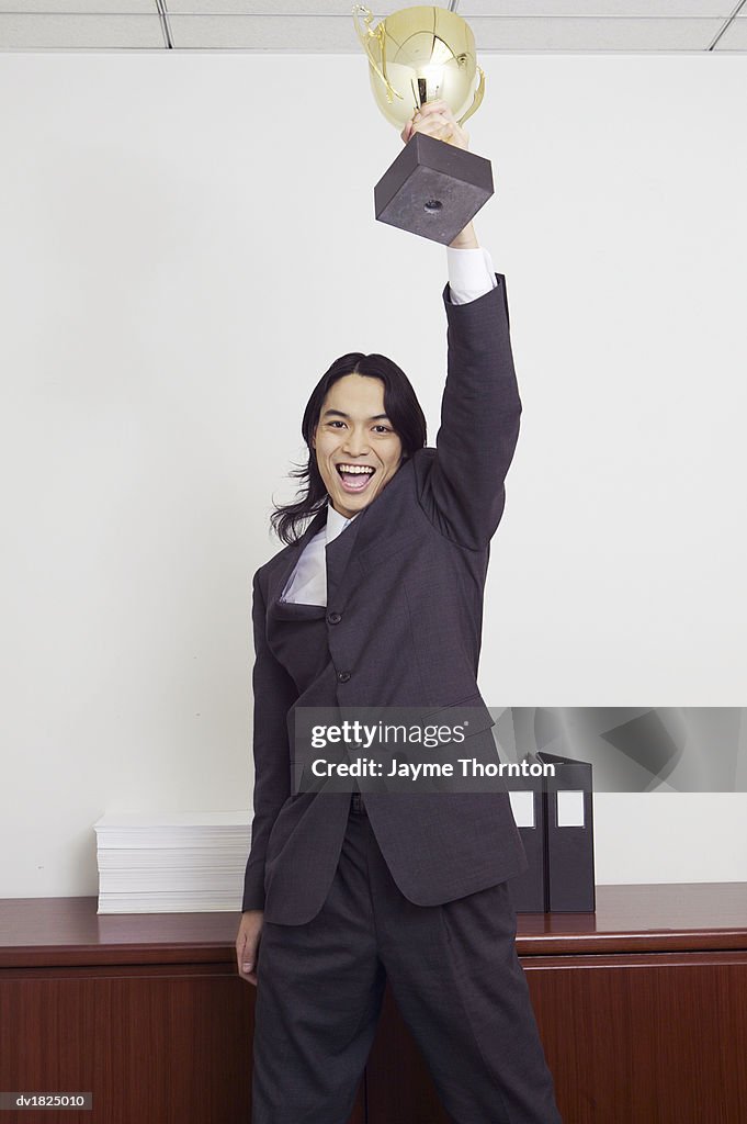 Portrait of a Businessman Holding a Trophy up and Cheering