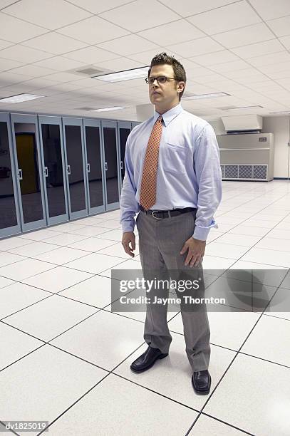 businessman standing in a server room near main-frame computers - main 個照片及圖片檔