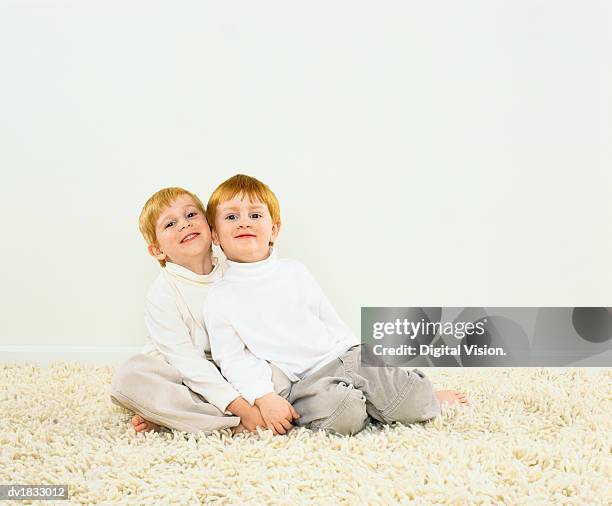 red haired twins wearing white polo neck jumpers sitting on a rug - polo neck stock-fotos und bilder