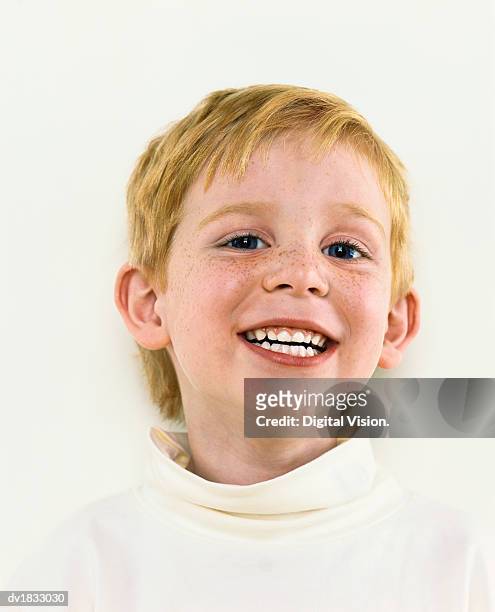 smiling young boy with freckles wearing a white polo neck jumper - polo neck stock-fotos und bilder