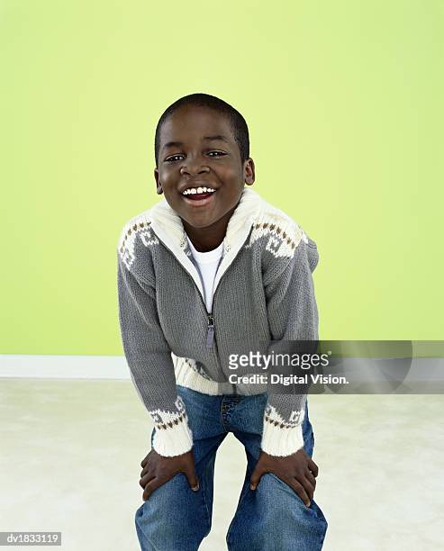 portrait of a young boy standing with hands on his knees and laughing - standing with hands on knees imagens e fotografias de stock